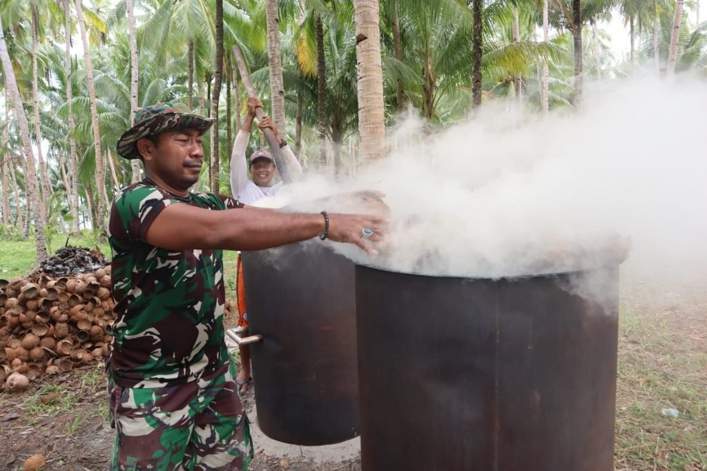 Personel Satgas TMMD Ke-118 Kodim 1501/Ternate Membantu Keluarga Asuh Membuat Arang Tempurung Kelapa